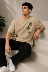 Back view of a man wearing a beige RARE INSIGHT oversized t-shirt with a green "Sorry But I Don't Care" graphic and star accents.