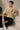 Back view of a man wearing a beige RARE INSIGHT oversized t-shirt with a green "Sorry But I Don't Care" graphic and star accents.