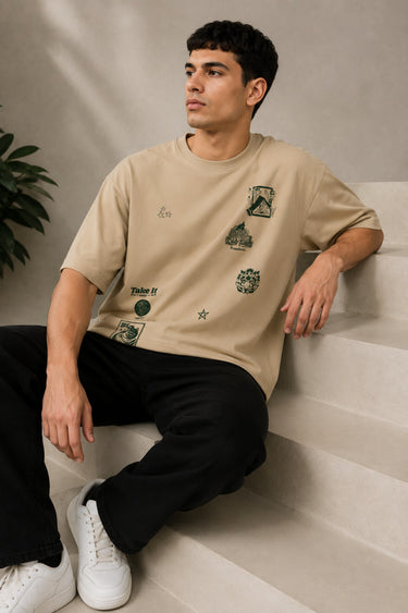 Back view of a man wearing a beige RARE INSIGHT oversized t-shirt with a green "Sorry But I Don't Care" graphic and star accents.