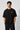 Model wearing a black oversized t-shirt with a small, embroidered Formula 1® logo in white, red, and gray on the chest. Casual streetwear style.