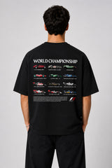Model wearing a black oversized t-shirt with a small, embroidered Formula 1® logo in white, red, and gray on the chest. Casual streetwear style. - black