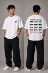 Model wearing a black oversized t-shirt with a small, embroidered Formula 1® logo in white, red, and gray on the chest. Casual streetwear style. - white