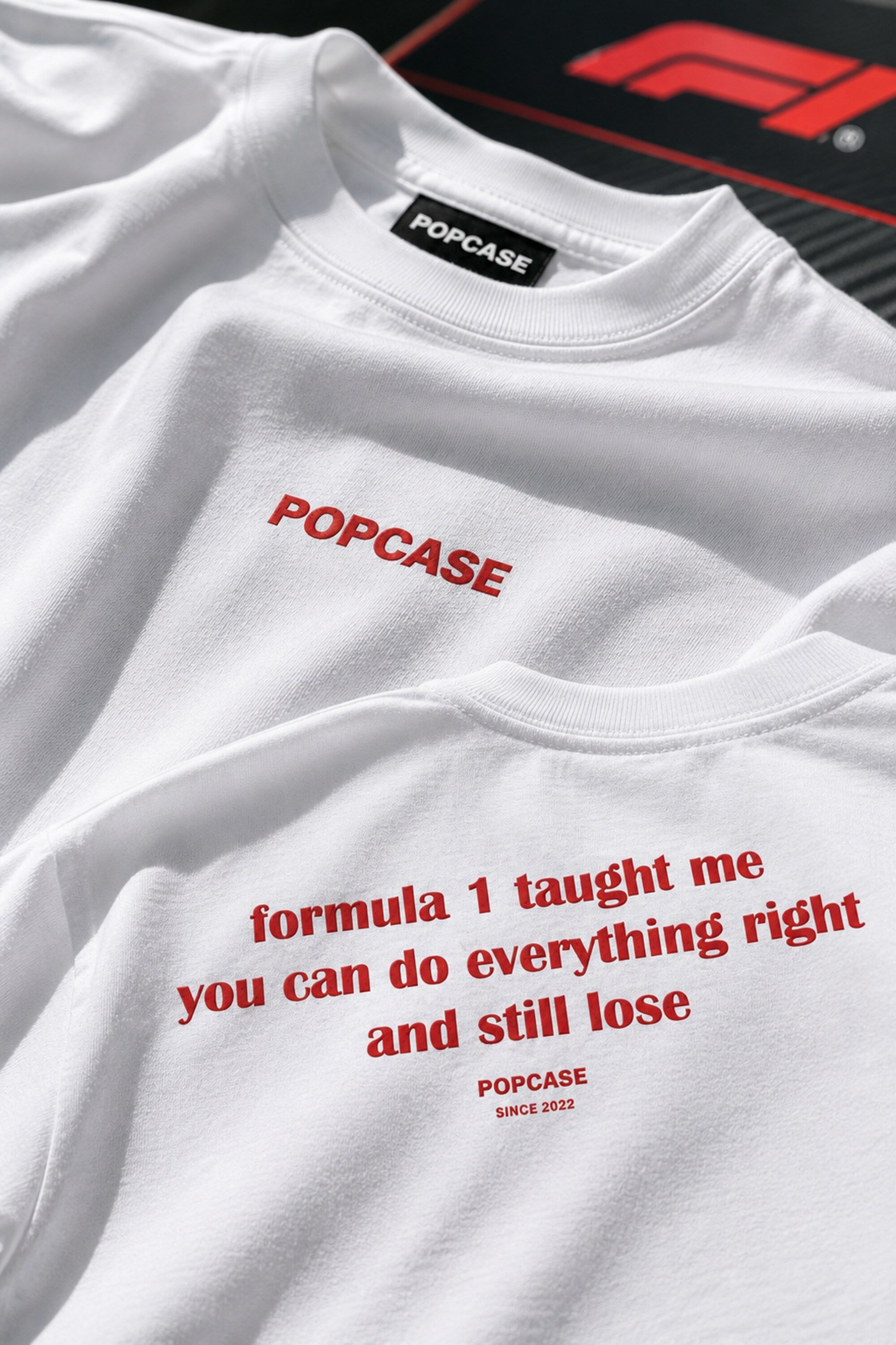 White sweatshirt with red text and 'POPCASE' branding on a black background with 'F1' logo.