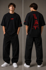 Man wearing white F1 Official oversized t-shirt with red F1 logo, black wide-leg jeans, and white sneakers, sitting on a black leather couch. - black