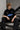 Model wearing a black Fast Feels Forever oversized t-shirt with graphic prints, sitting on a leather couch.