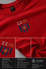 Man wearing a red FCB Messi fan oversized t-shirt, black pants, and white sneakers, sitting on a brown couch.