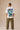 Man wearing a white oversized Real Madrid t-shirt with a circular club crest logo, paired with olive green pants and black sneakers, posing casually with hands in pockets.