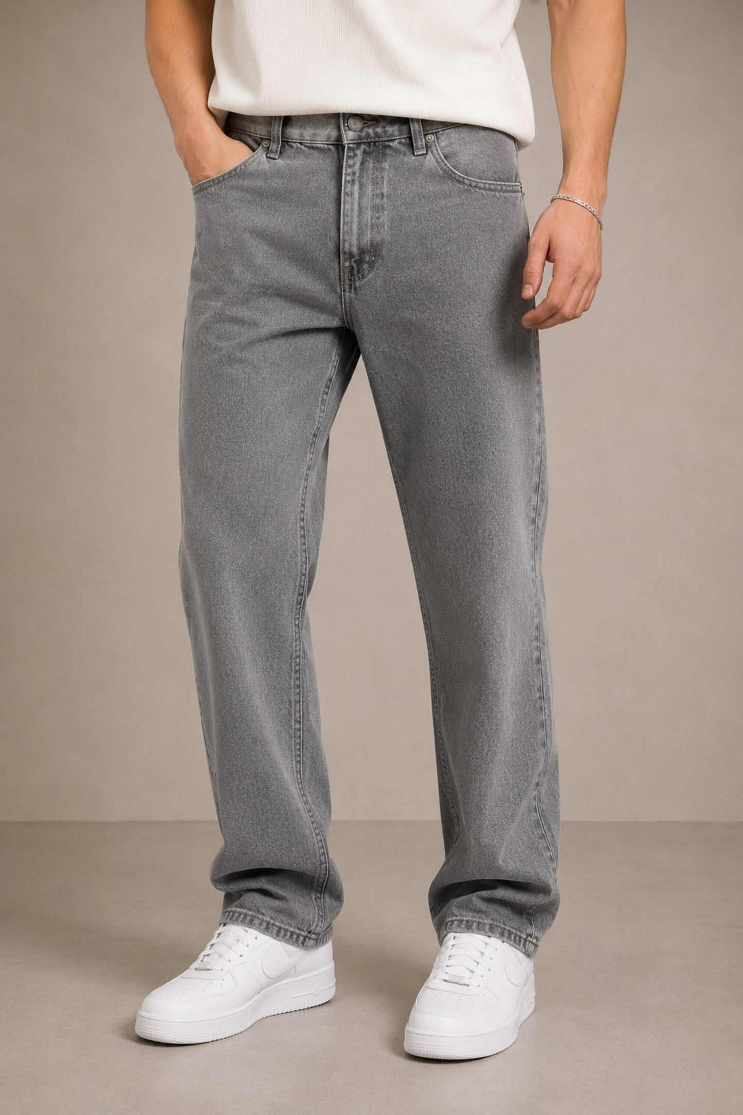 Person wearing gray jeans and white sneakers on a beige background