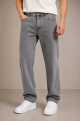 Person wearing gray jeans and white sneakers on a beige background