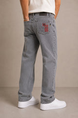 Person wearing gray jeans with a visible brand logo on a beige background