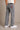 Person wearing gray jeans with a visible brand logo on a beige background