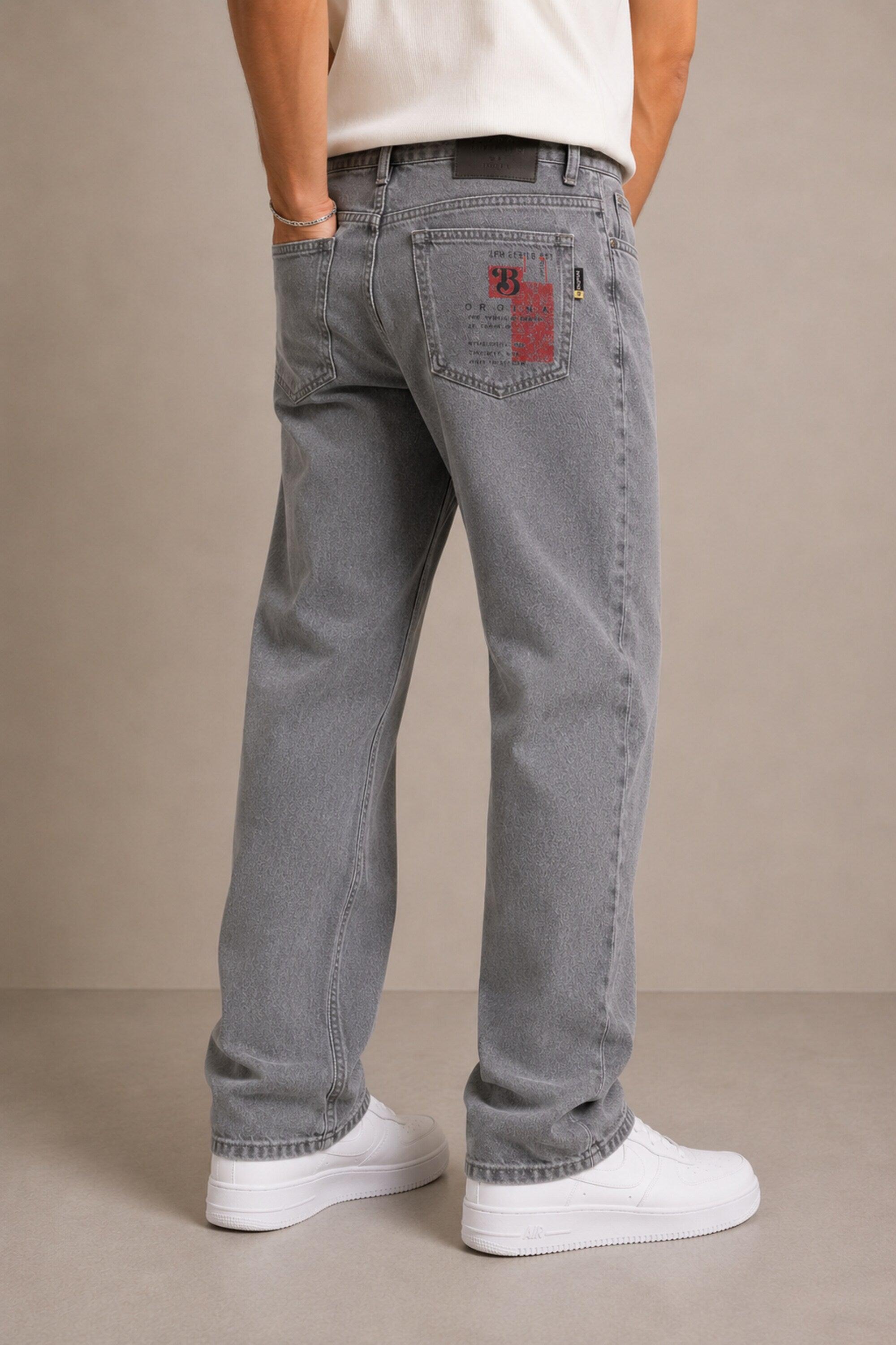Person wearing gray jeans with a visible brand logo on a beige background