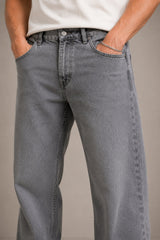 Person wearing gray jeans with a plain background