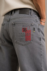 Gray jeans with a brand logo on the back pocket against a neutral background