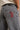 Gray jeans with a brand logo on the back pocket against a neutral background