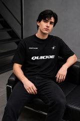 Black QUICKE oversized t-shirt featuring bold white graphic print on the chest and back. Showcasing premium fabric details and relaxed fit.