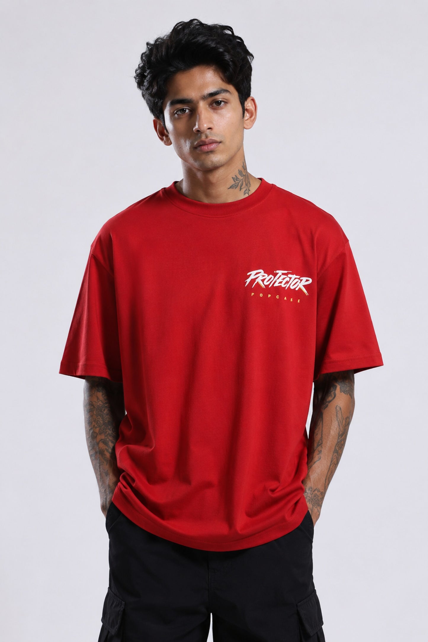 Red oversized t-shirt with 'PROJECTOR HANUMANJI' graphic design of a warrior monkey god and 'POPCASE' logo, worn by a man.