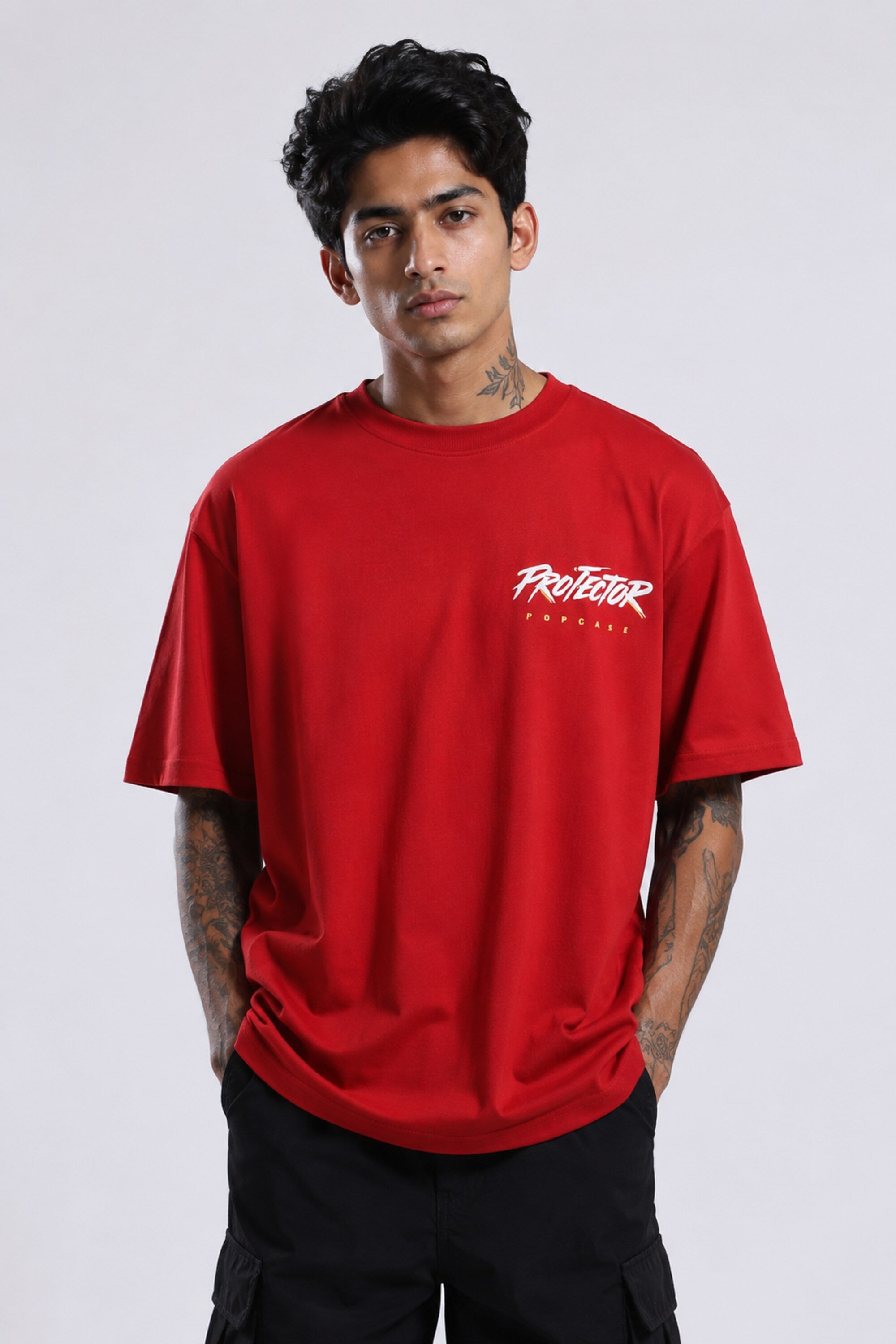 Red oversized t-shirt with 'PROJECTOR HANUMANJI' graphic design of a warrior monkey god and 'POPCASE' logo, worn by a man.