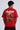 Red oversized t-shirt with 'PROJECTOR HANUMANJI' graphic design of a warrior monkey god and 'POPCASE' logo, worn by a man.
