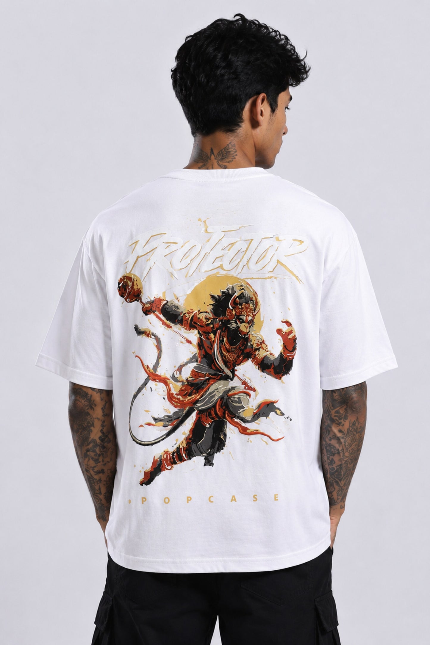 Red oversized t-shirt with 'PROJECTOR HANUMANJI' graphic design of a warrior monkey god and 'POPCASE' logo, worn by a man.