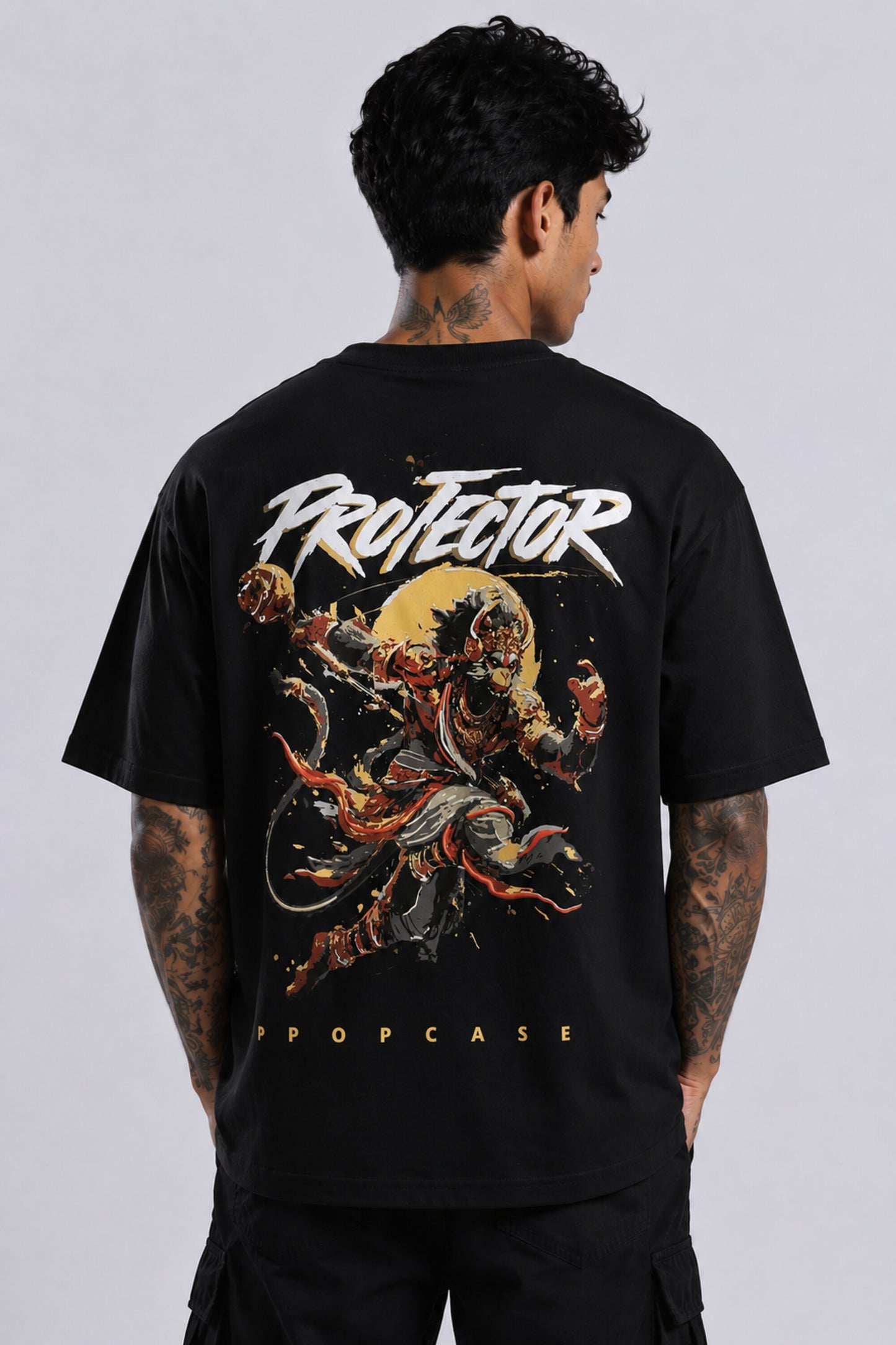 Red oversized t-shirt with 'PROJECTOR HANUMANJI' graphic design of a warrior monkey god and 'POPCASE' logo, worn by a man.