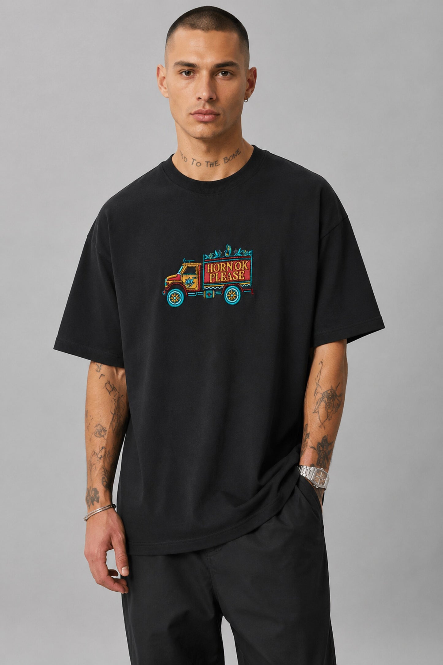 Back view of a man wearing a black HORN OK PLEASE oversized t-shirt with gold 'POPCASE' logo on the upper back.