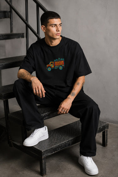 Back view of a man wearing a black HORN OK PLEASE oversized t-shirt with gold 'POPCASE' logo on the upper back.