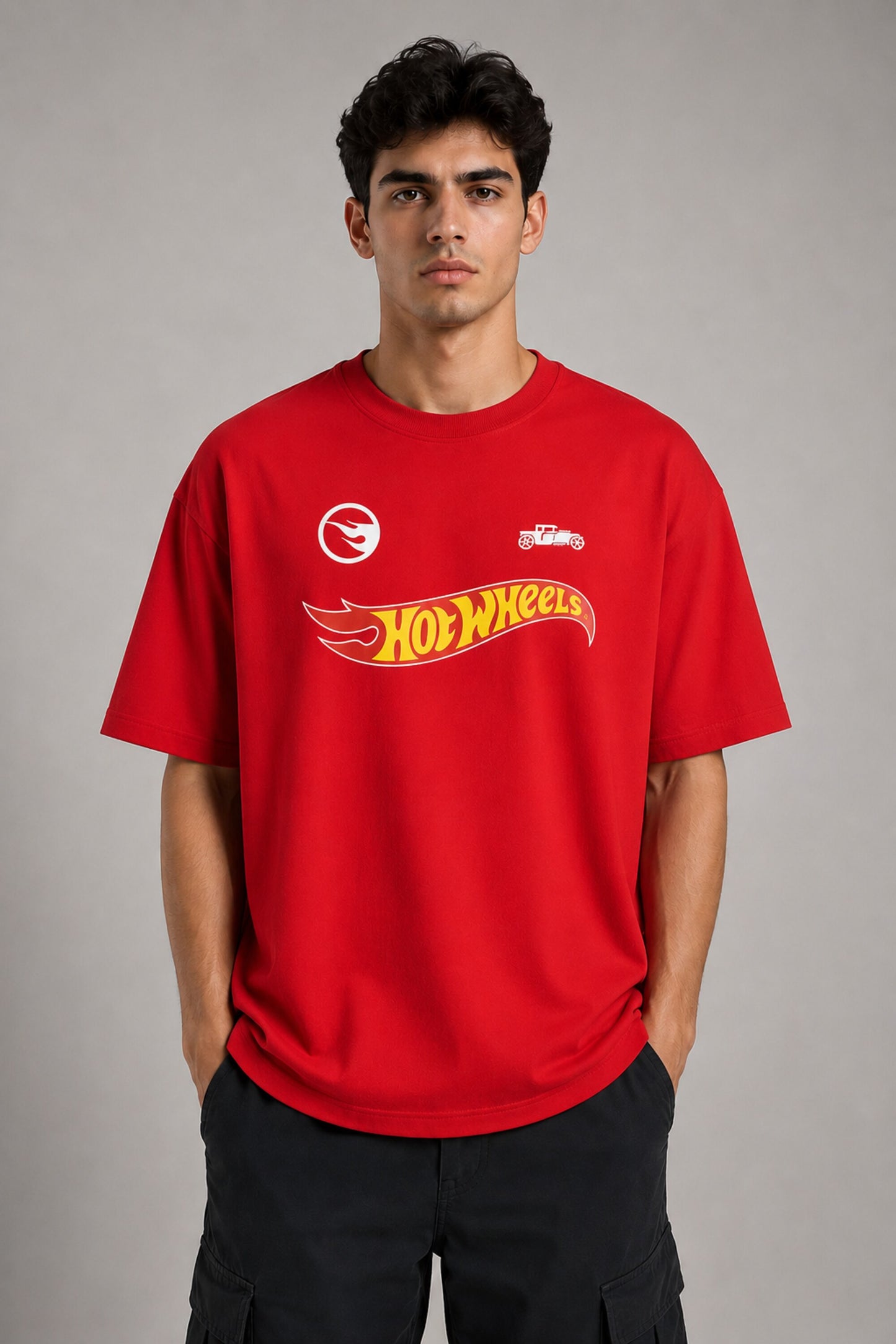 Couple wearing matching red oversized Hot Wheels t-shirts and black bottoms, standing on stairs. Feature iconic Hot Wheels logo. - red