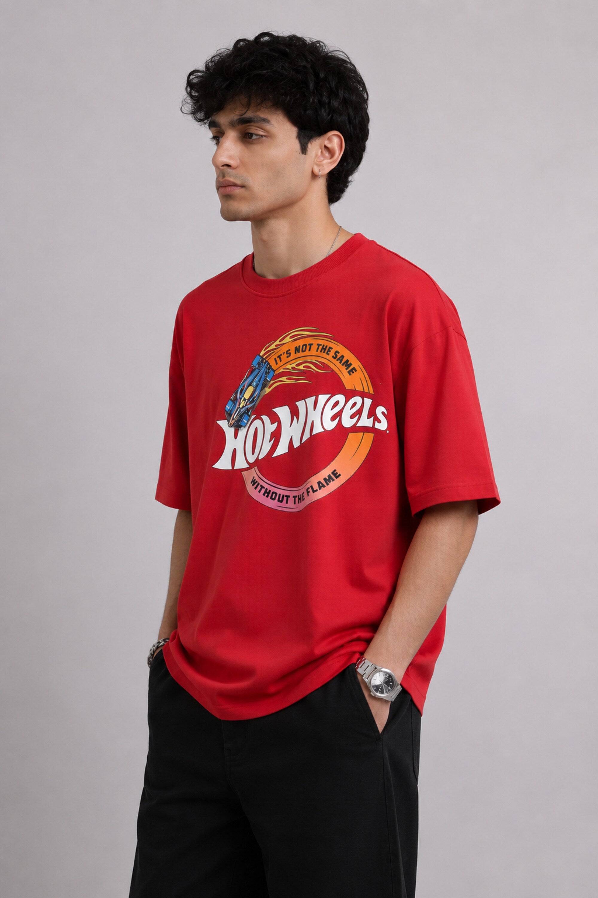 Model wearing a black oversized t-shirt with a vintage Hot Wheels graphic and flames. The tee has a relaxed fit and is paired with black pants.
