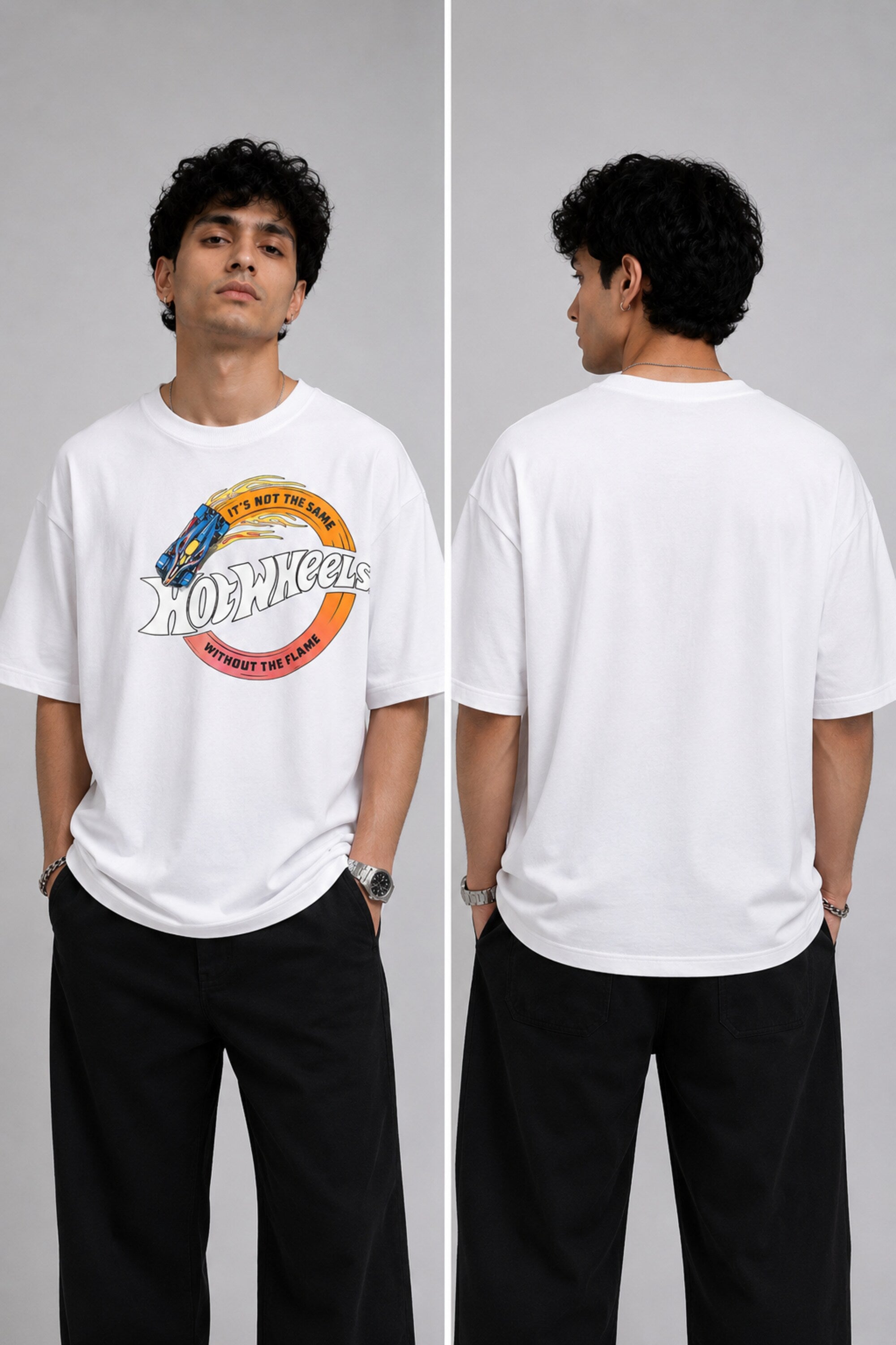 Model wearing a black oversized t-shirt with a vintage Hot Wheels graphic and flames. The tee has a relaxed fit and is paired with black pants. - white