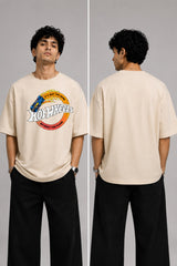 Model wearing a black oversized t-shirt with a vintage Hot Wheels graphic and flames. The tee has a relaxed fit and is paired with black pants. - beige