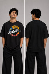 Model wearing a black oversized t-shirt with a vintage Hot Wheels graphic and flames. The tee has a relaxed fit and is paired with black pants.