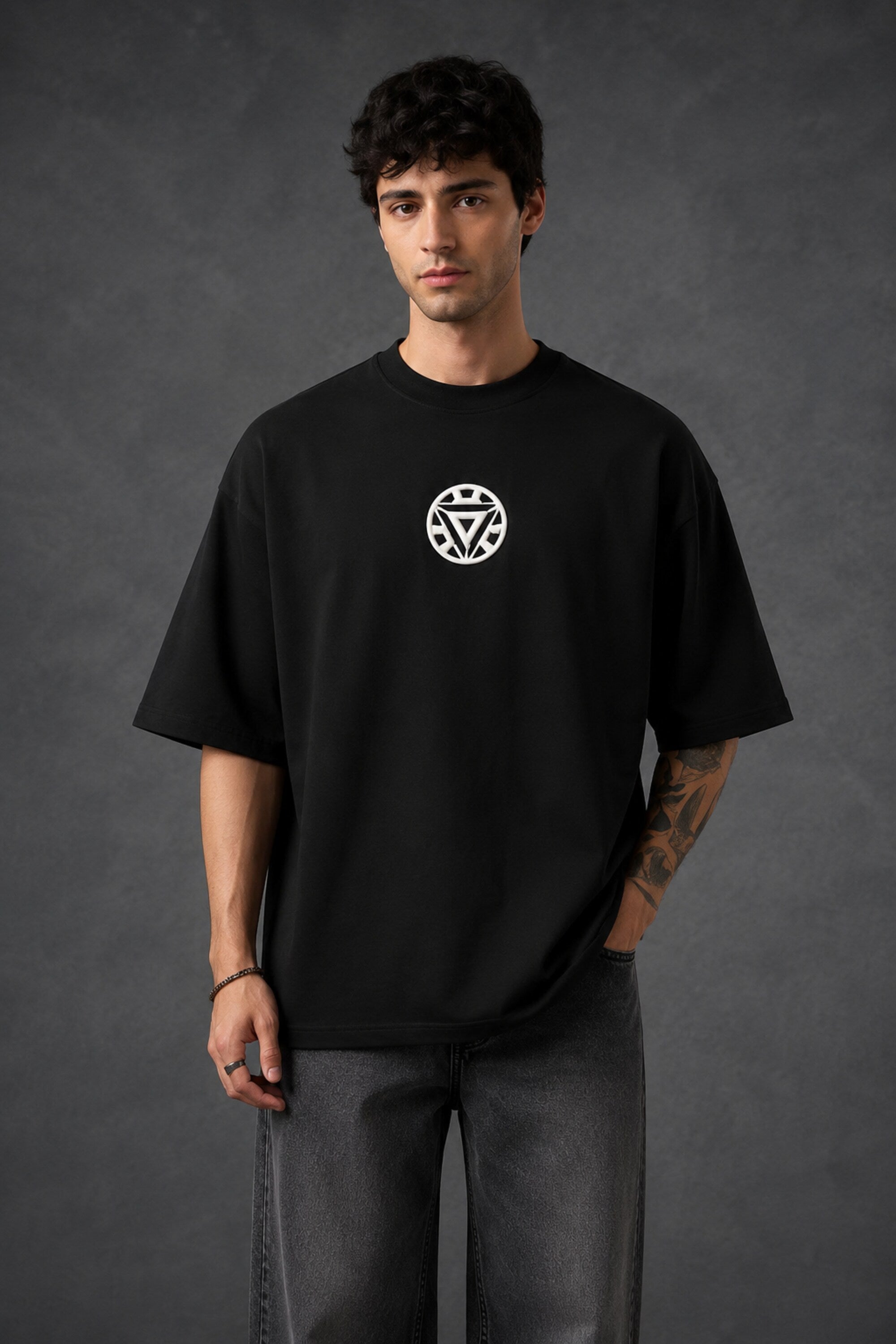 Couple wearing black Iron Man Jarvish oversized t-shirts. Man's back shows "IRON MAN" logo. Woman's front shows Iron Man arc reactor logo. Dark grey background.