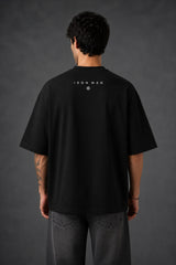 Couple wearing black Iron Man Jarvish oversized t-shirts. Man's back shows "IRON MAN" logo. Woman's front shows Iron Man arc reactor logo. Dark grey background.