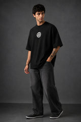 Couple wearing black Iron Man Jarvish oversized t-shirts. Man's back shows "IRON MAN" logo. Woman's front shows Iron Man arc reactor logo. Dark grey background.