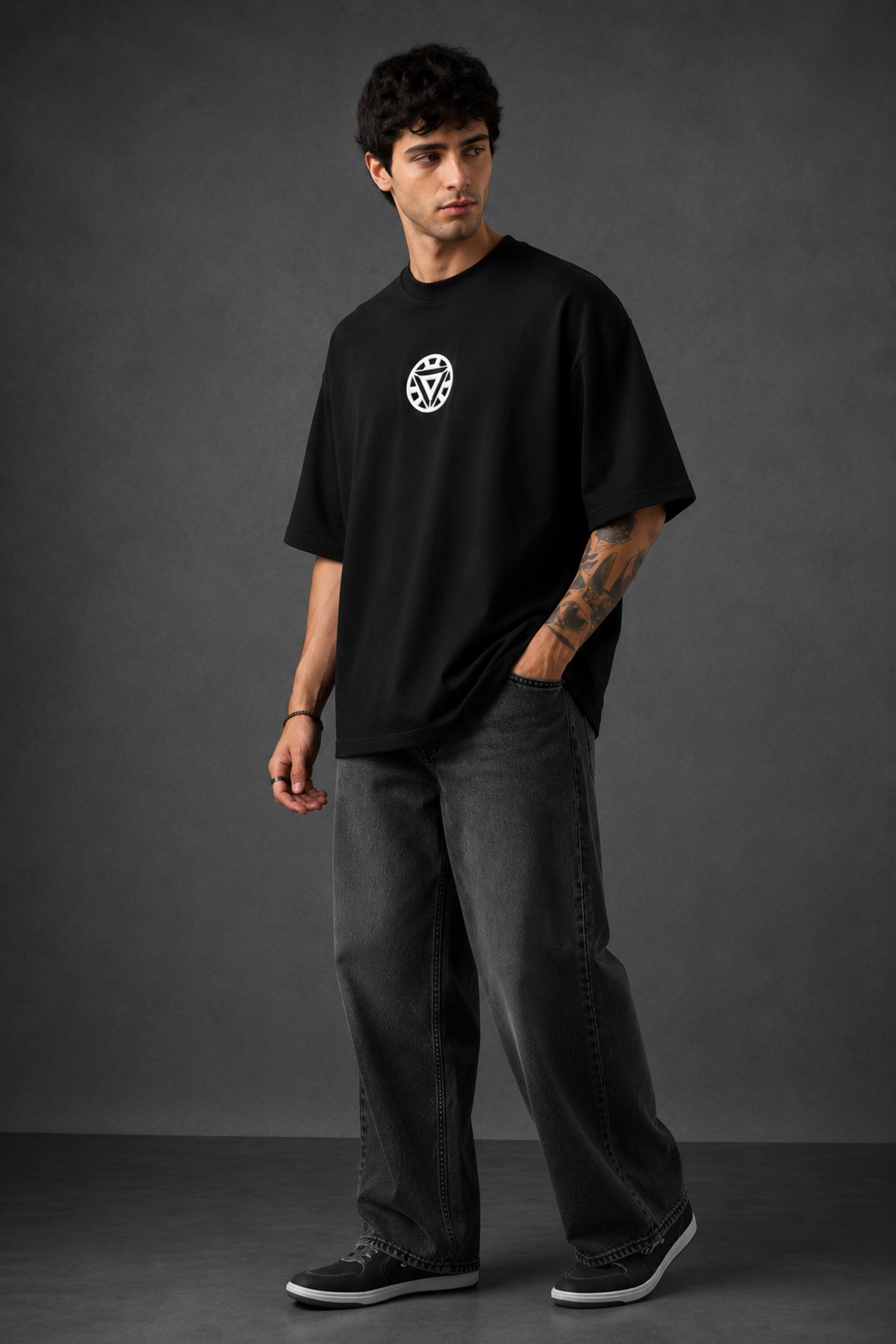 Couple wearing black Iron Man Jarvish oversized t-shirts. Man's back shows "IRON MAN" logo. Woman's front shows Iron Man arc reactor logo. Dark grey background.