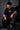 Couple wearing black Iron Man Jarvish oversized t-shirts. Man's back shows "IRON MAN" logo. Woman's front shows Iron Man arc reactor logo. Dark grey background.