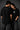 Couple wearing black Iron Man Jarvish oversized t-shirts. Man's back shows "IRON MAN" logo. Woman's front shows Iron Man arc reactor logo. Dark grey background.