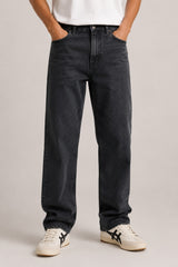 Person wearing black jeans and white sneakers on a plain background