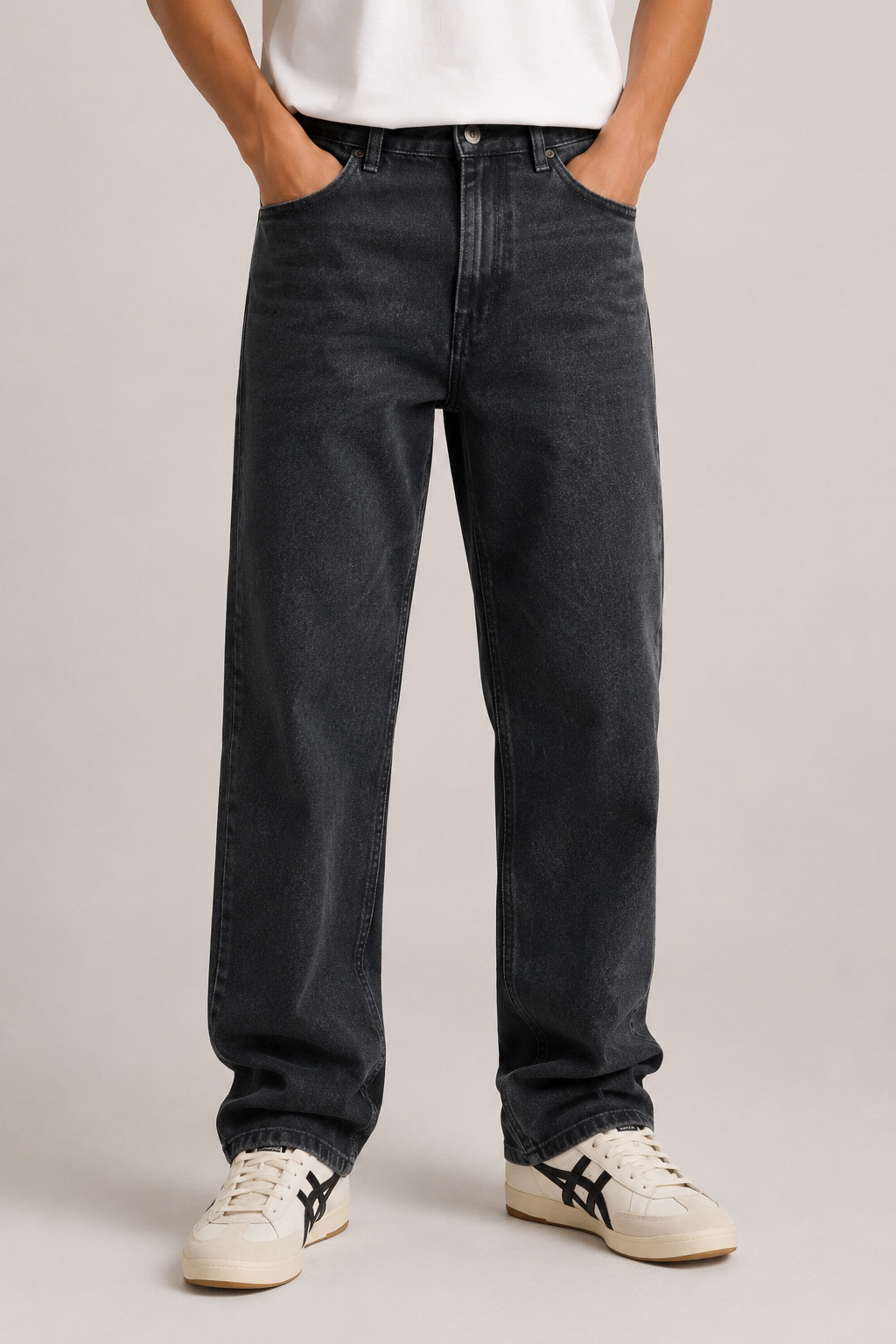 Person wearing black jeans and white sneakers on a plain background