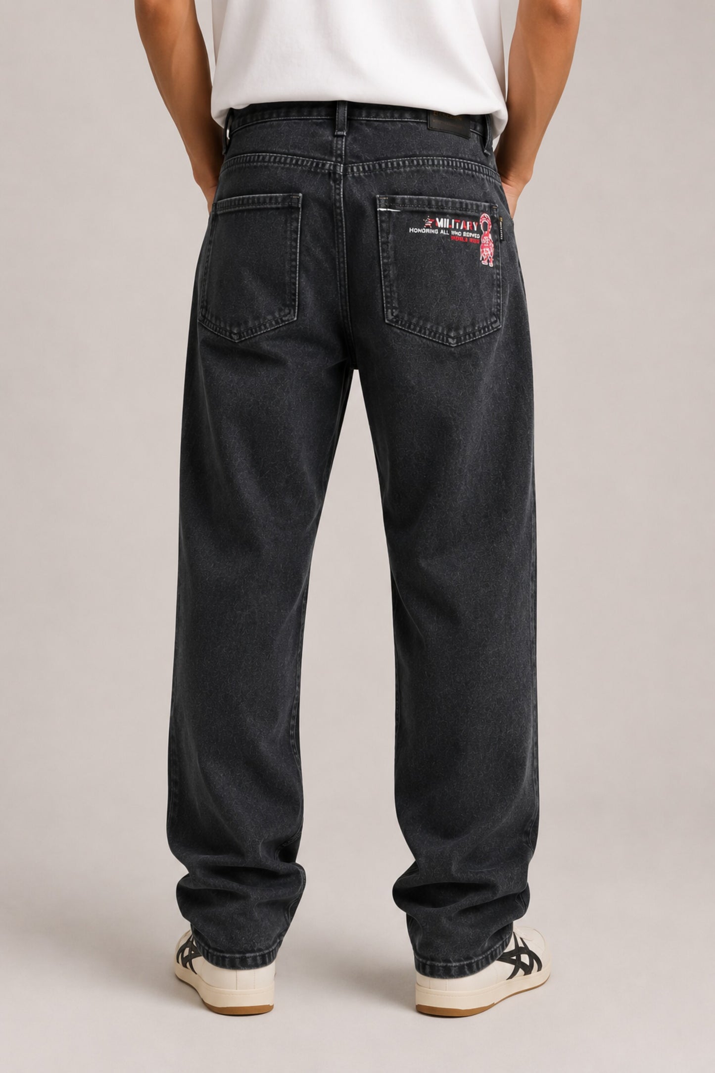 Person wearing black jeans with visible branding on a plain background