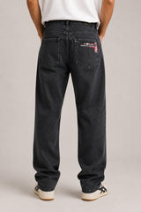 Person wearing black jeans with visible branding on a plain background