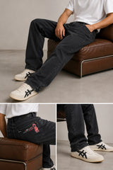 Person wearing dark jeans and white sneakers sitting on a brown leather chair.
