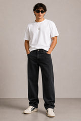 Person wearing a white t-shirt, black jeans, and sunglasses against a plain background