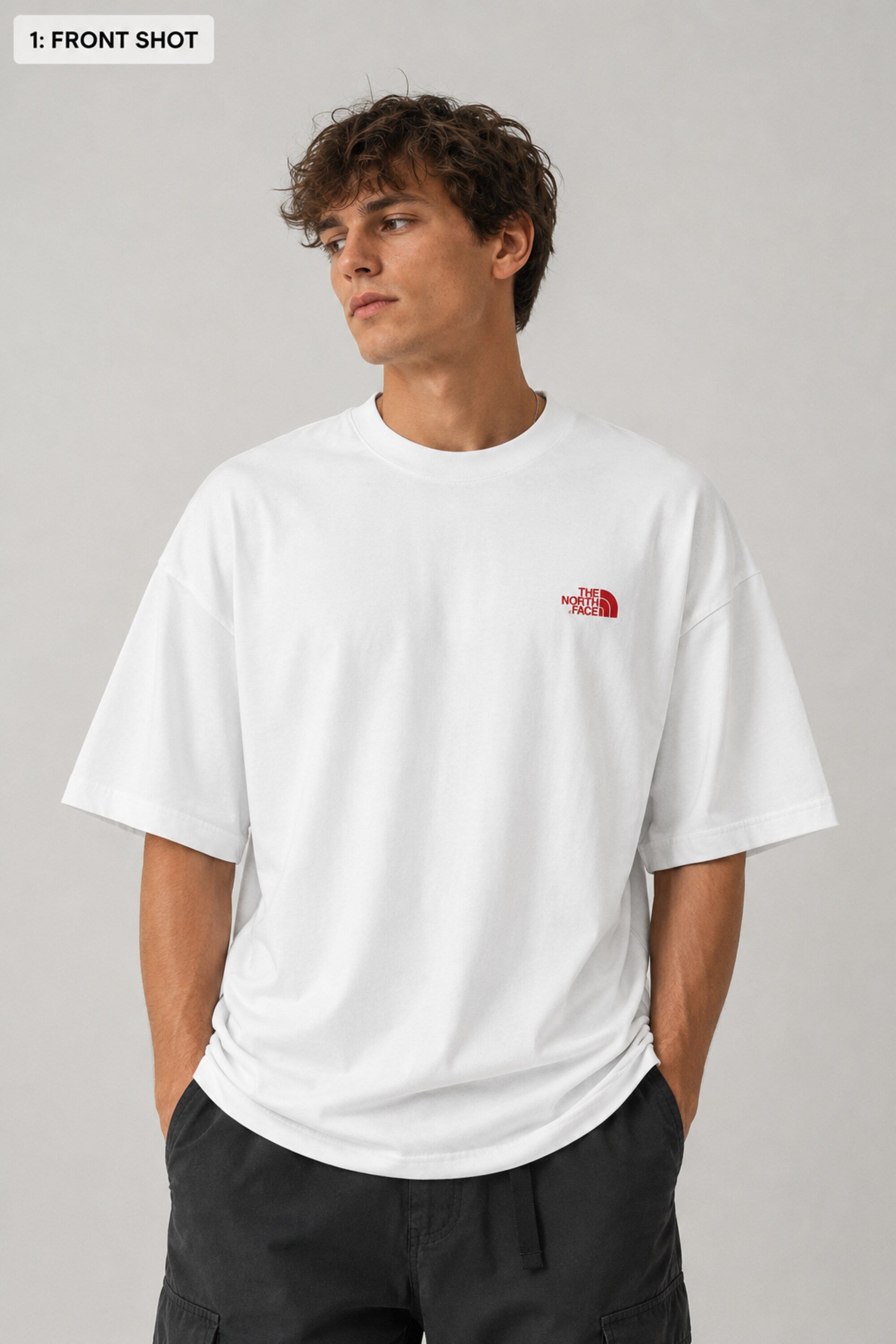 Model wearing a white POP-FROM-THE-NORTH oversized t-shirt with a small red logo on the chest, styled with black cargo pants, showcasing a relaxed streetwear fit.