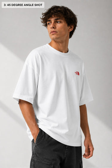 Model wearing a white POP-FROM-THE-NORTH oversized t-shirt with a small red logo on the chest, styled with black cargo pants, showcasing a relaxed streetwear fit.