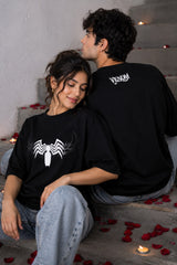 Two people sitting on steps with black shirts featuring spider-like designs.