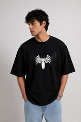 Person wearing a black t-shirt with a white spider logo on a plain background