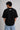 Person wearing a black t-shirt with 'Venom' logo on the back against a gray background
