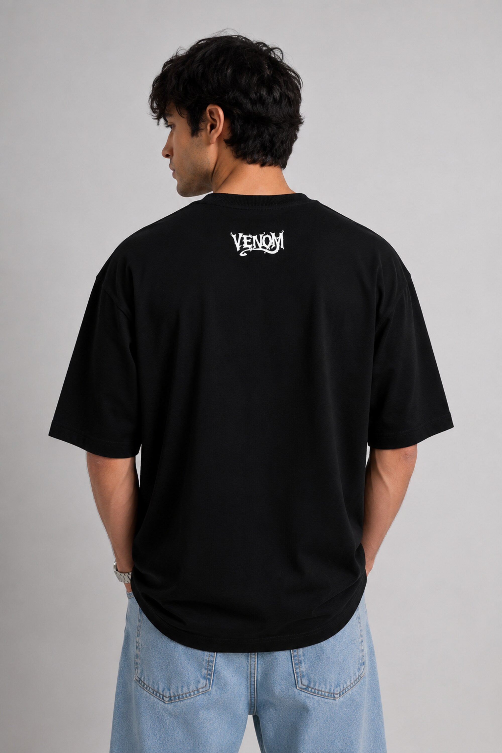 Person wearing a black t-shirt with 'Venom' logo on the back against a gray background